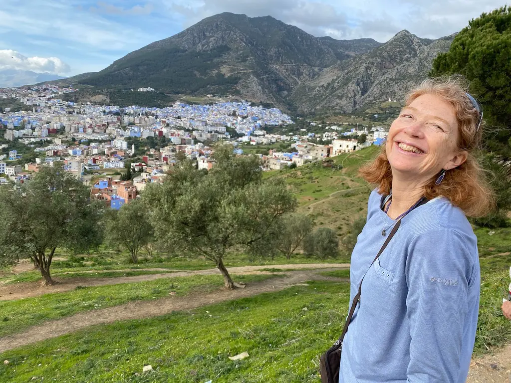 A picture of a woman smiling in front of a scenic town